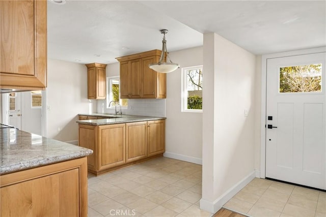 kitchen featuring decorative light fixtures, baseboards, light tile patterned flooring, decorative backsplash, and light stone countertops