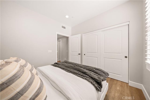 bedroom featuring baseboards, visible vents, light wood-style flooring, recessed lighting, and a closet