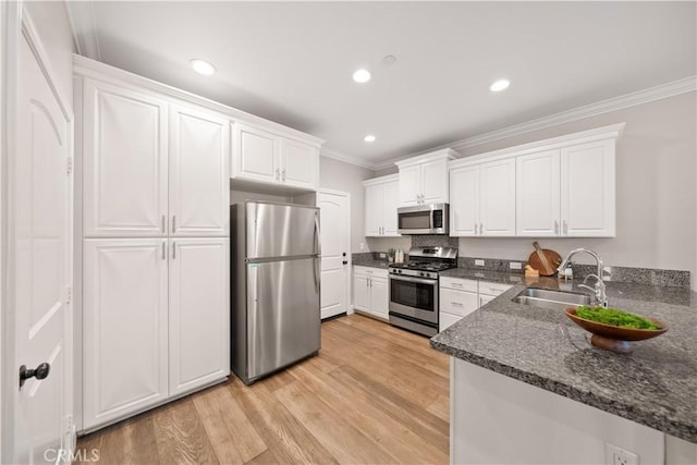 kitchen with a sink, appliances with stainless steel finishes, ornamental molding, and white cabinets