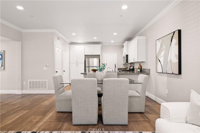 dining room featuring crown molding, wood finished floors, and visible vents