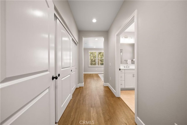 hallway with recessed lighting, baseboards, and light wood-style flooring