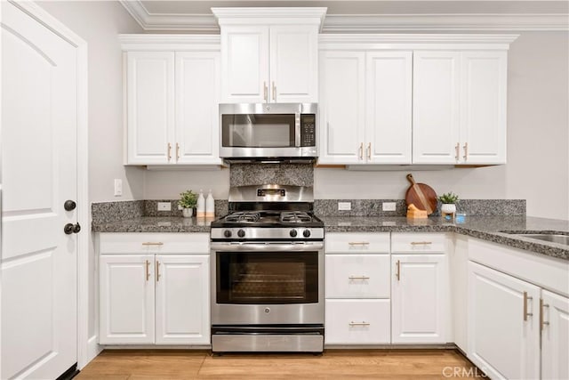 kitchen featuring stainless steel appliances, light wood-style floors, ornamental molding, and white cabinetry