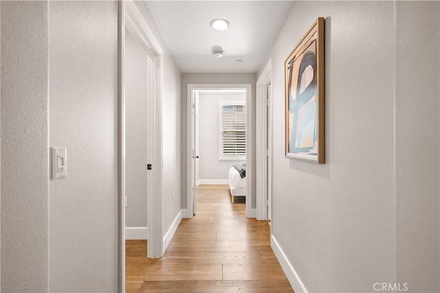 hall with light wood-style flooring and baseboards