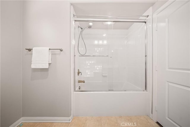 bathroom with baseboards and bath / shower combo with glass door