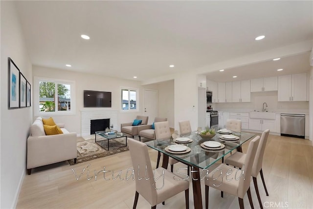 dining area featuring recessed lighting, light wood-style flooring, a brick fireplace, and baseboards