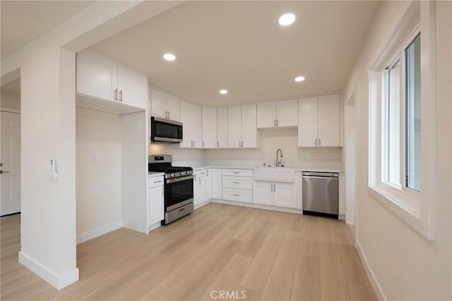 kitchen with light wood finished floors, recessed lighting, appliances with stainless steel finishes, and a sink