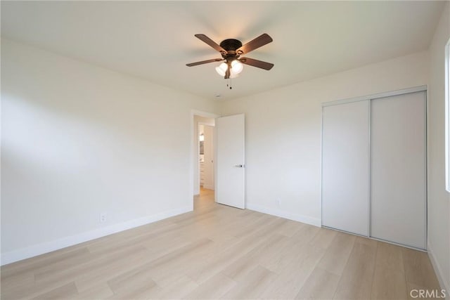 unfurnished bedroom with a closet, light wood-style flooring, a ceiling fan, and baseboards