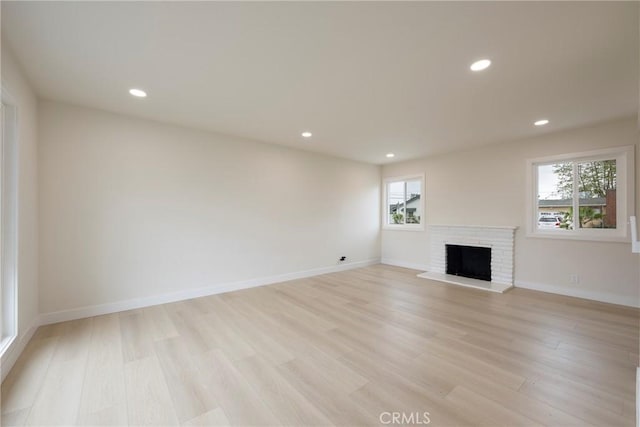 unfurnished living room featuring recessed lighting, light wood-type flooring, baseboards, and a fireplace