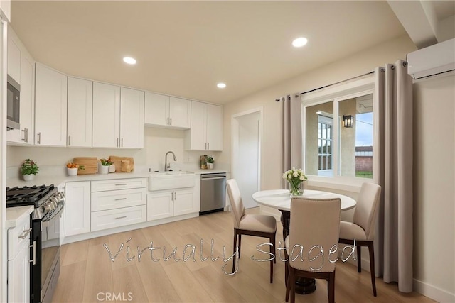 kitchen featuring a sink, stainless steel appliances, white cabinets, light wood finished floors, and light countertops