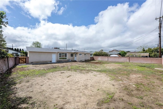 back of property with stucco siding and fence