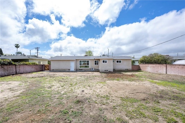 back of house with a fenced backyard and stucco siding