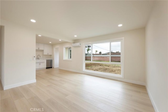 unfurnished living room with baseboards, recessed lighting, light wood-type flooring, and a wall mounted AC