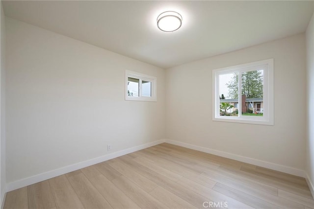 unfurnished room with baseboards and light wood-style floors