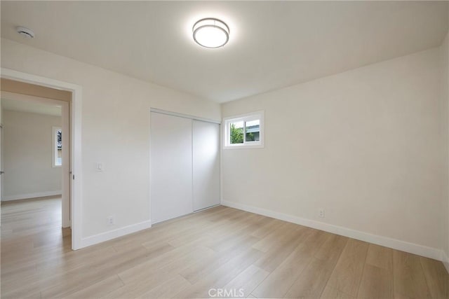 spare room with baseboards and light wood-style flooring