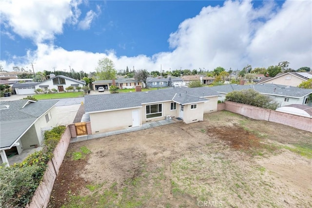 exterior space featuring stucco siding, a residential view, roof with shingles, and a fenced backyard