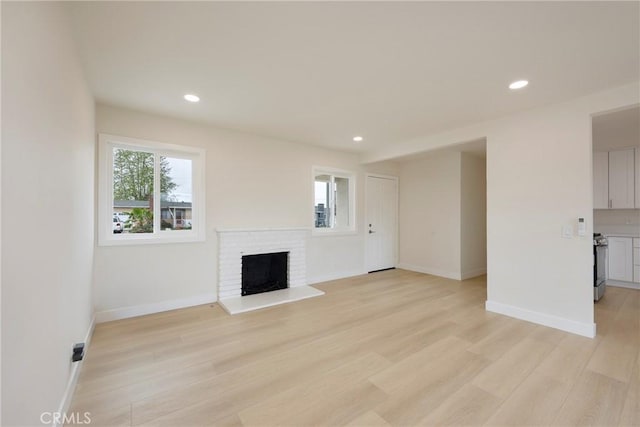 unfurnished living room featuring recessed lighting, baseboards, light wood-style floors, and a brick fireplace