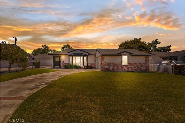 ranch-style home featuring concrete driveway, a yard, and fence