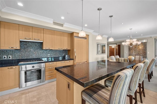 kitchen with light brown cabinetry, backsplash, stainless steel appliances, and a breakfast bar