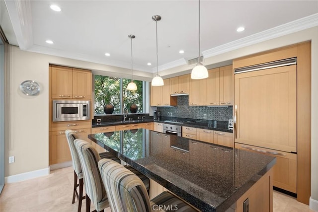 kitchen with a sink, a kitchen breakfast bar, backsplash, a kitchen island, and built in appliances