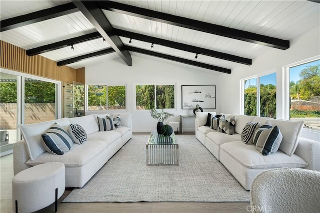 living area featuring wood finished floors, vaulted ceiling with beams, and a healthy amount of sunlight