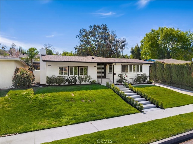 ranch-style home featuring a front lawn and fence