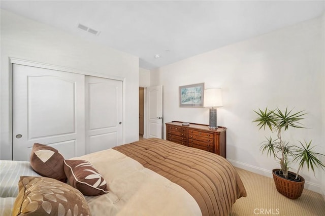 bedroom with carpet flooring, baseboards, visible vents, and a closet