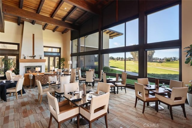 sunroom / solarium with vaulted ceiling with beams, wood ceiling, and a large fireplace