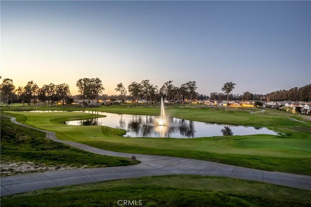 view of community with a lawn, golf course view, and a water view