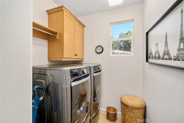 washroom with cabinet space, baseboards, and washer and clothes dryer