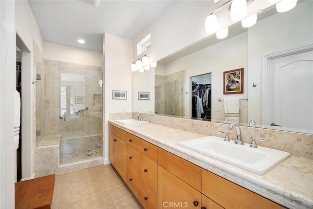 bathroom featuring double vanity, a stall shower, a walk in closet, and a sink