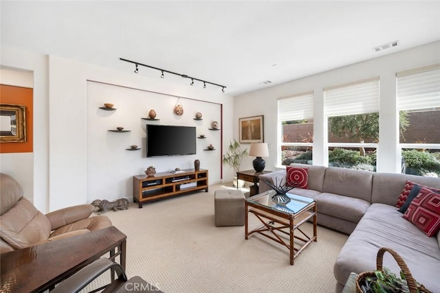 carpeted living room featuring rail lighting, plenty of natural light, and visible vents