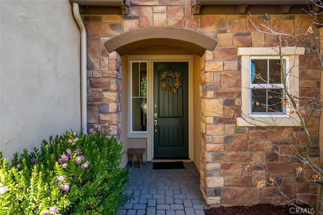 entrance to property featuring stone siding and stucco siding