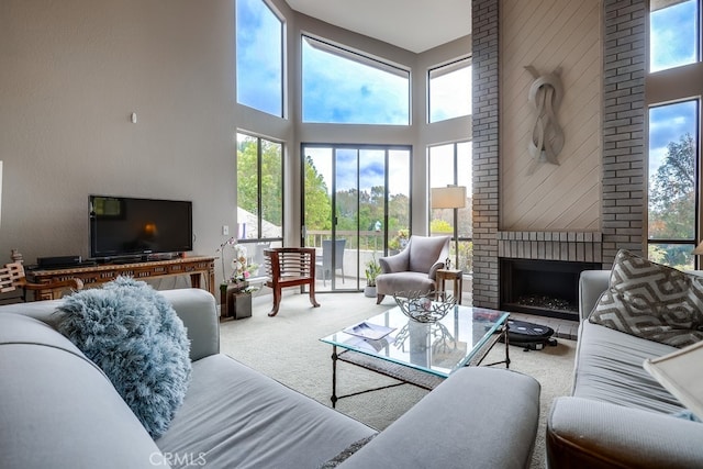 carpeted living room with a brick fireplace, a healthy amount of sunlight, and a towering ceiling