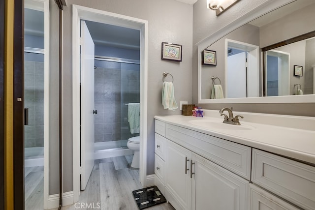 bathroom with vanity, a shower stall, toilet, and wood finished floors