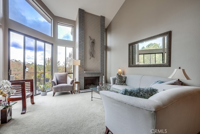 carpeted living area with a brick fireplace and a towering ceiling