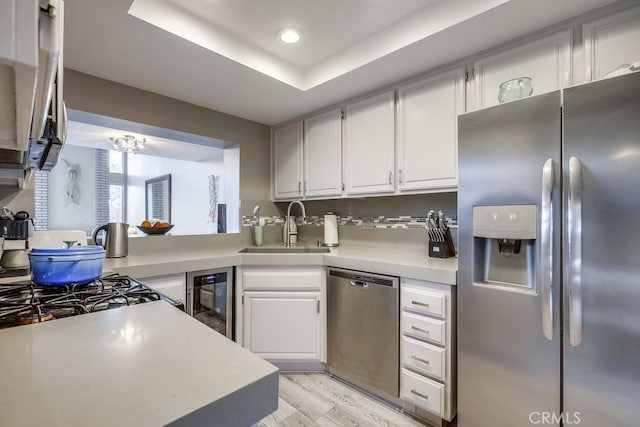 kitchen with a sink, white cabinetry, stainless steel appliances, wine cooler, and light countertops