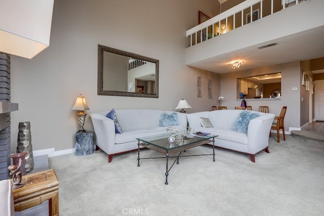 carpeted living room featuring visible vents, a fireplace, baseboards, and a towering ceiling