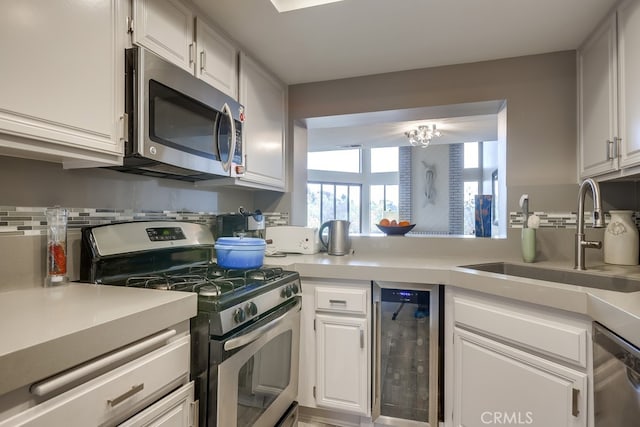 kitchen with a sink, light countertops, wine cooler, white cabinets, and appliances with stainless steel finishes