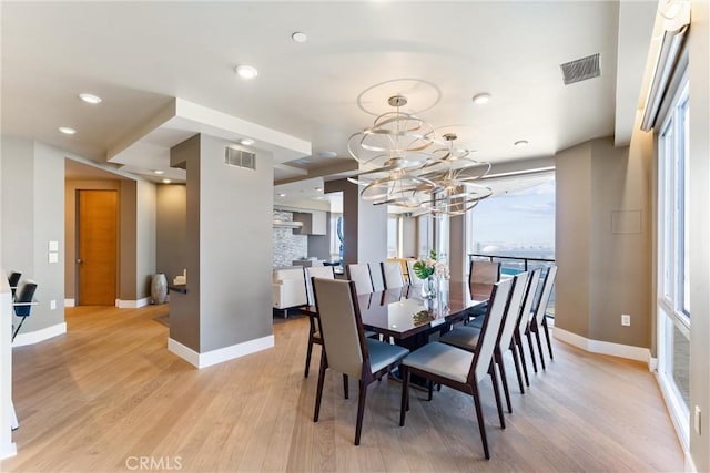 dining area with a chandelier, visible vents, baseboards, and light wood-style floors