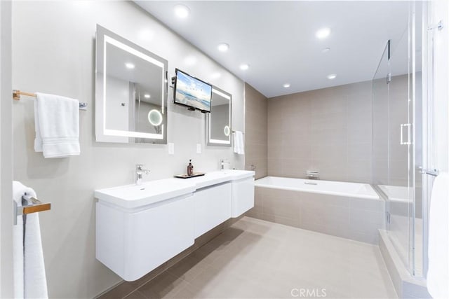 bathroom featuring tile patterned flooring, a shower stall, double vanity, a bath, and a sink