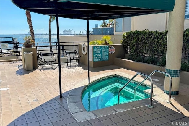 view of pool with a patio area, a water view, and a hot tub