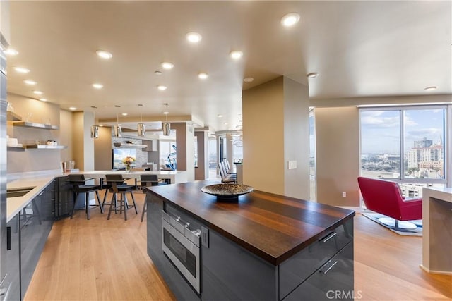 kitchen with stainless steel microwave, modern cabinets, light wood-style floors, and wooden counters