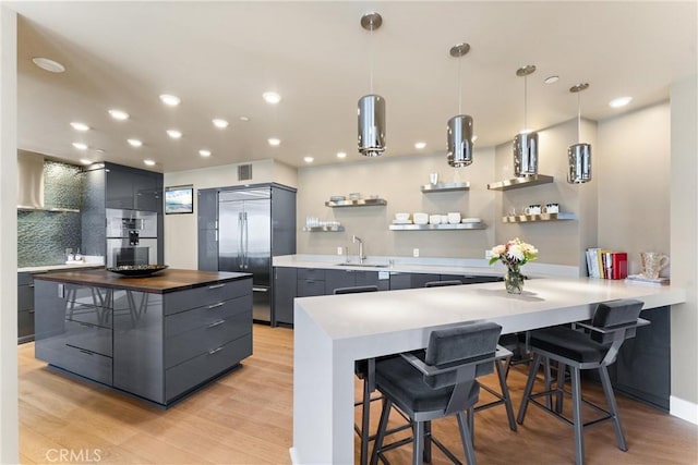 kitchen featuring open shelves, a sink, appliances with stainless steel finishes, a kitchen bar, and modern cabinets