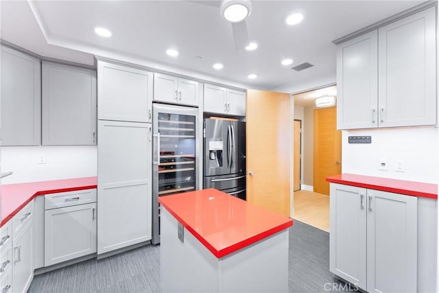 kitchen featuring visible vents, beverage cooler, recessed lighting, stainless steel fridge with ice dispenser, and light countertops