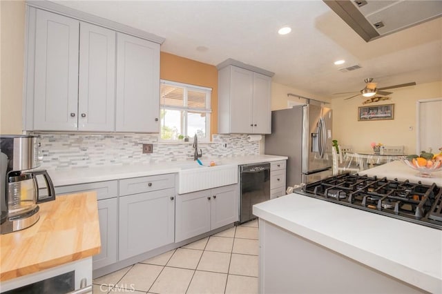 kitchen featuring stainless steel refrigerator with ice dispenser, a sink, tasteful backsplash, light tile patterned flooring, and dishwasher