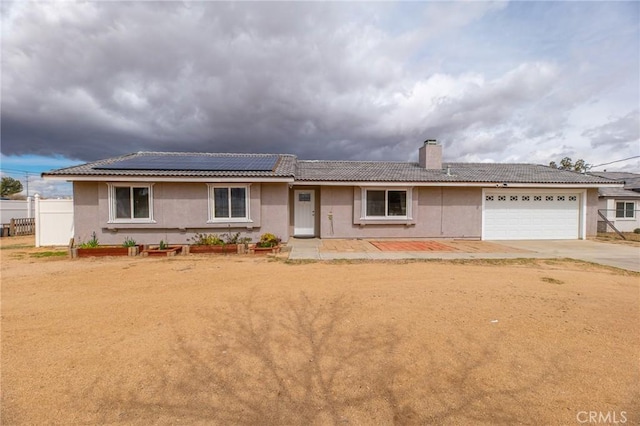 single story home with solar panels, fence, a tiled roof, concrete driveway, and stucco siding