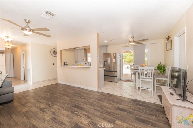 living area with a ceiling fan, visible vents, light wood finished floors, and baseboards