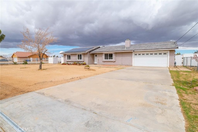 ranch-style house with fence, concrete driveway, an attached garage, a chimney, and a tiled roof