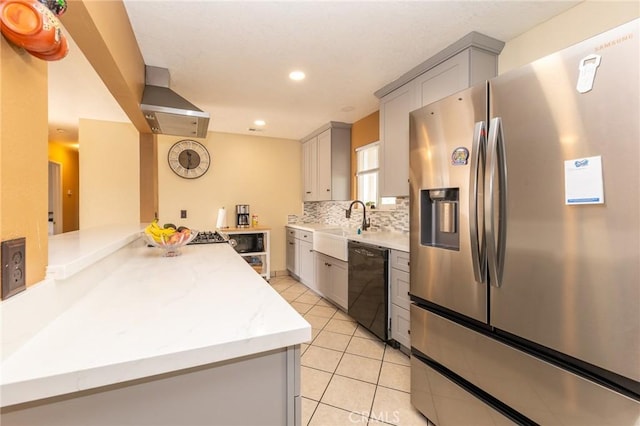 kitchen with gray cabinets, wall chimney exhaust hood, stainless steel refrigerator with ice dispenser, and black dishwasher