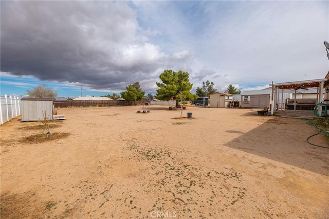 view of yard featuring a shed, an outdoor structure, and fence